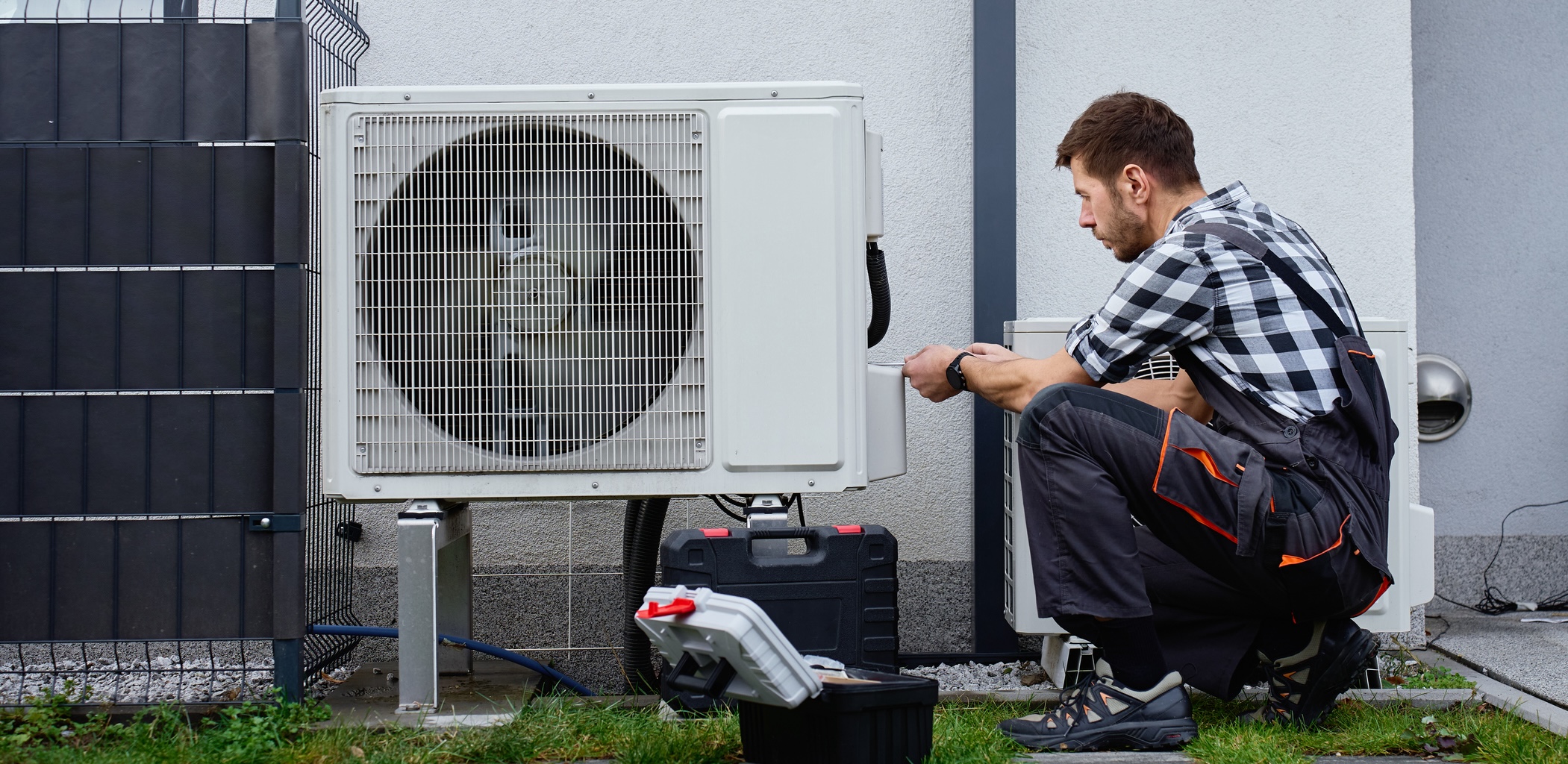Technician performing maintenance on outdoor heat pump unit